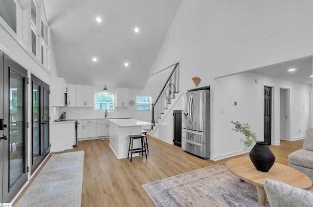 kitchen with a breakfast bar area, light countertops, white cabinetry, a kitchen island, and stainless steel fridge with ice dispenser