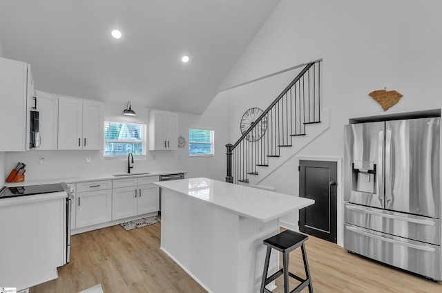 kitchen with white cabinets, stainless steel refrigerator with ice dispenser, a sink, and a center island