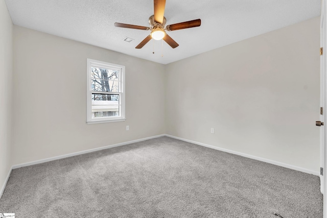 carpeted empty room with visible vents, a textured ceiling, baseboards, and a ceiling fan