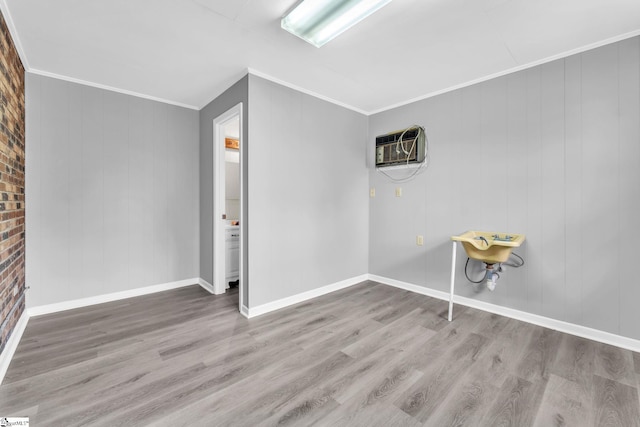 unfurnished room featuring baseboards, a wall mounted air conditioner, wood finished floors, and crown molding