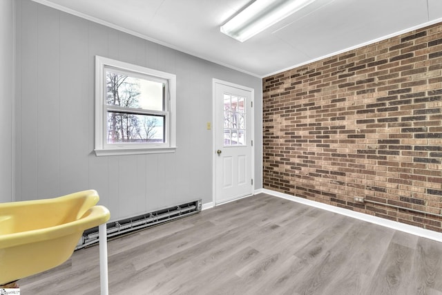 interior space featuring a baseboard radiator, light wood-style flooring, brick wall, baseboards, and crown molding