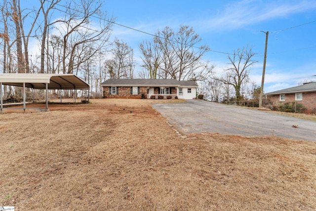 ranch-style home with aphalt driveway, a carport, and a front yard