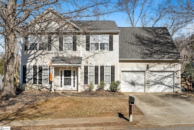 colonial inspired home with a garage, concrete driveway, and roof with shingles