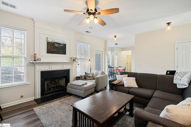 living room with dark wood-style flooring, visible vents, and plenty of natural light