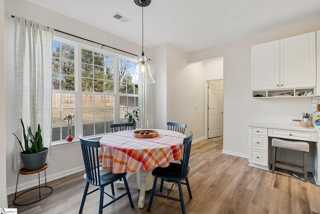 dining area featuring light wood finished floors, visible vents, and baseboards