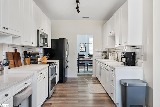 kitchen featuring appliances with stainless steel finishes, white cabinets, a sink, and visible vents