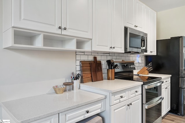 kitchen featuring light stone counters, open shelves, stainless steel appliances, backsplash, and white cabinetry