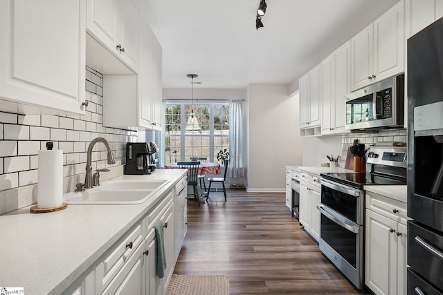 kitchen featuring stainless steel appliances, white cabinets, light countertops, and hanging light fixtures