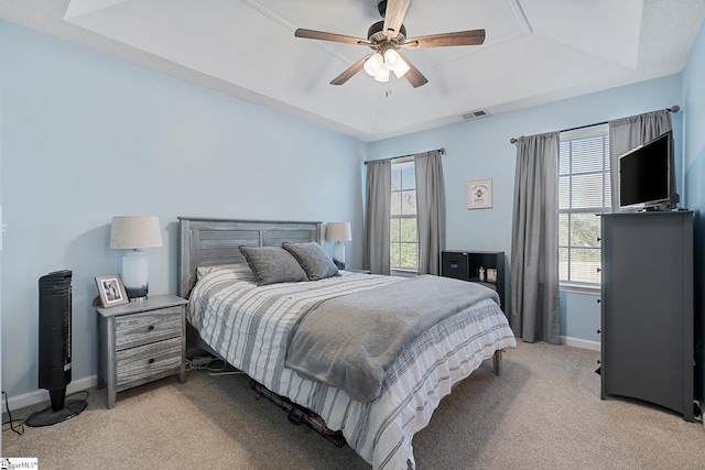 bedroom featuring light carpet, visible vents, a tray ceiling, and baseboards