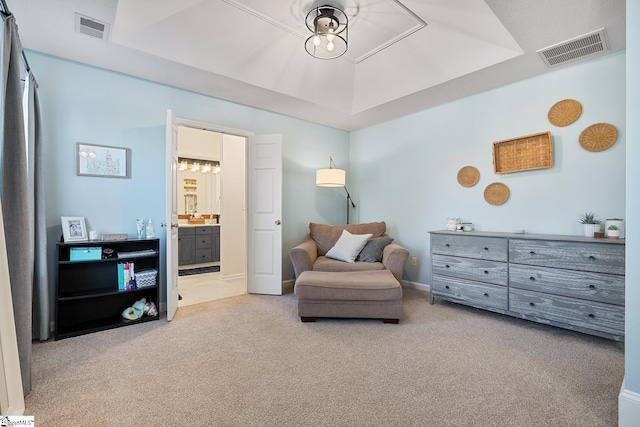 living area with light carpet, baseboards, visible vents, and a raised ceiling