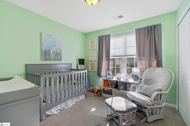 carpeted bedroom with a textured ceiling, a closet, visible vents, and baseboards