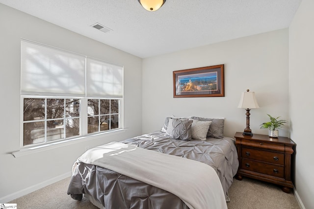 bedroom with carpet floors, visible vents, a textured ceiling, and baseboards