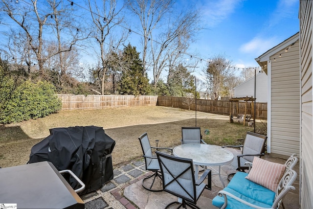 view of patio featuring outdoor dining space, a fenced backyard, and grilling area