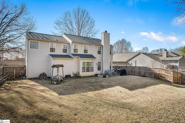 back of property featuring a yard, a chimney, and a fenced backyard