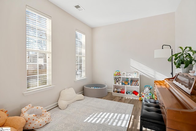 game room with wood finished floors, visible vents, and baseboards