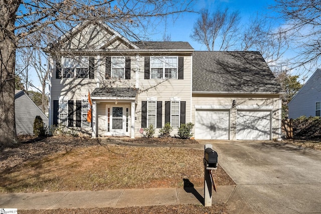 colonial house featuring a shingled roof, concrete driveway, and an attached garage