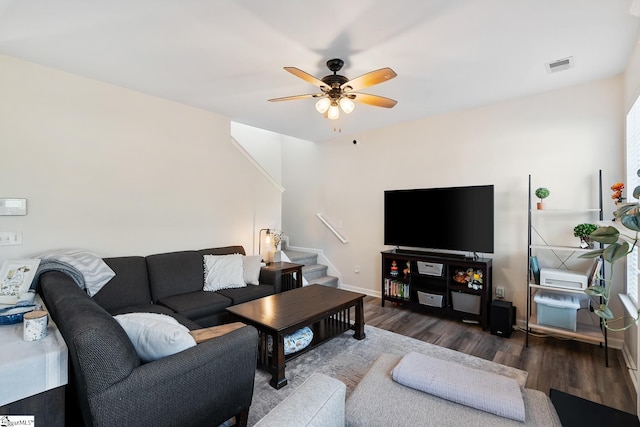 living area with ceiling fan, wood finished floors, visible vents, baseboards, and stairway