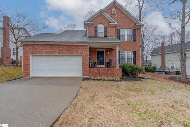 traditional home with concrete driveway, brick siding, an attached garage, and a front yard