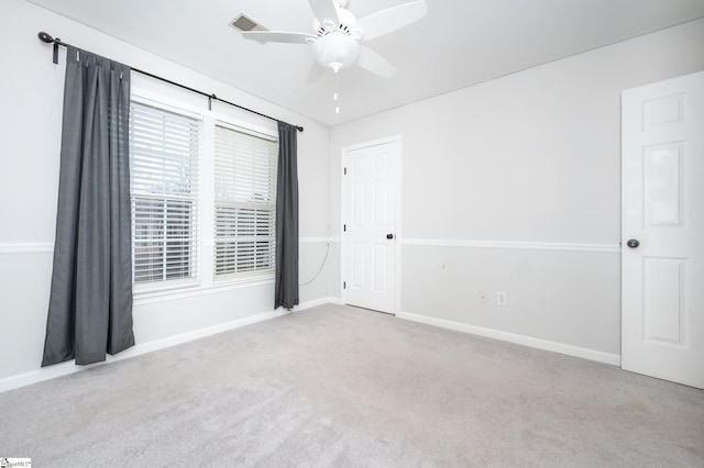 spare room with ceiling fan, baseboards, visible vents, and light colored carpet