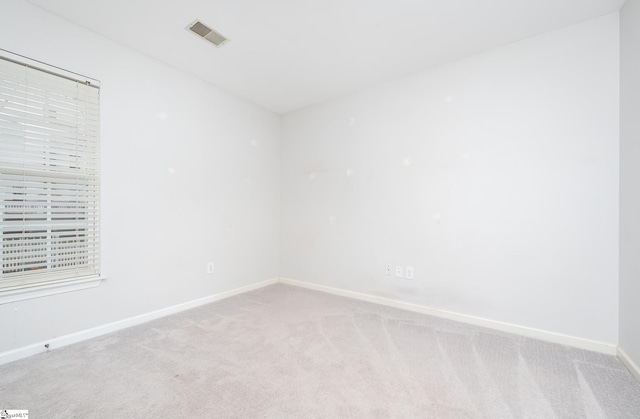 spare room with baseboards, visible vents, and light colored carpet