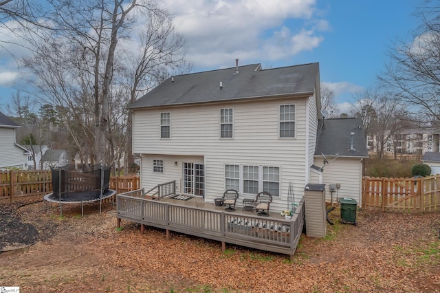 back of house featuring a trampoline, a fenced backyard, and a wooden deck