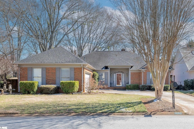 view of front of home featuring a garage, brick siding, driveway, and a front lawn