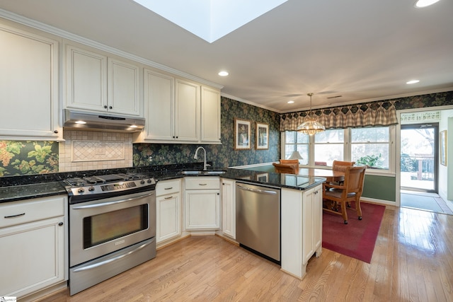 kitchen with stainless steel appliances, hanging light fixtures, a sink, a peninsula, and under cabinet range hood