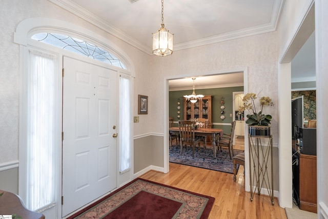 entrance foyer with baseboards, light wood-type flooring, a chandelier, and crown molding