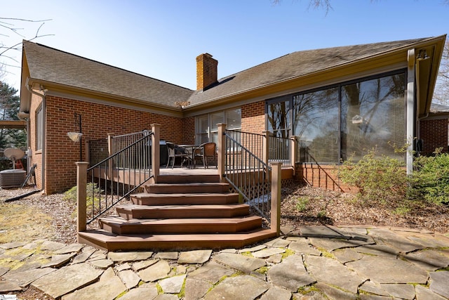 back of property featuring a shingled roof, a chimney, stairway, a patio area, and brick siding