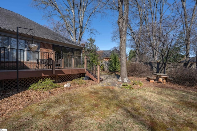 view of yard with a wooden deck, a sunroom, and fence