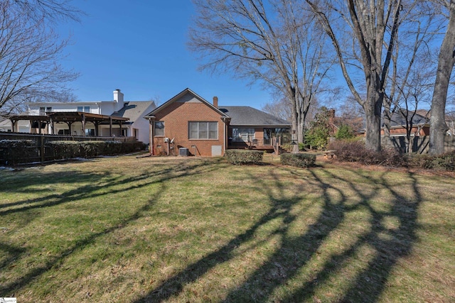 rear view of property with brick siding, a lawn, and a chimney