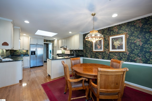 dining space featuring light wood-type flooring, a skylight, wallpapered walls, and recessed lighting