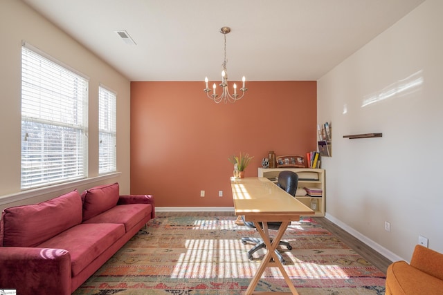 office space featuring a chandelier, visible vents, baseboards, and wood finished floors