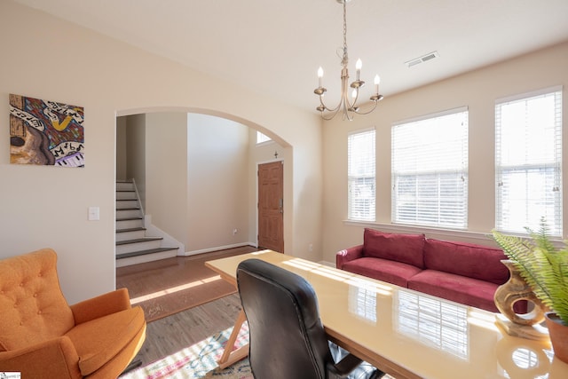 office space with arched walkways, plenty of natural light, wood finished floors, and visible vents