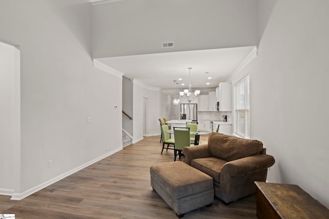 sitting room featuring visible vents, baseboards, stairway, light wood finished floors, and an inviting chandelier