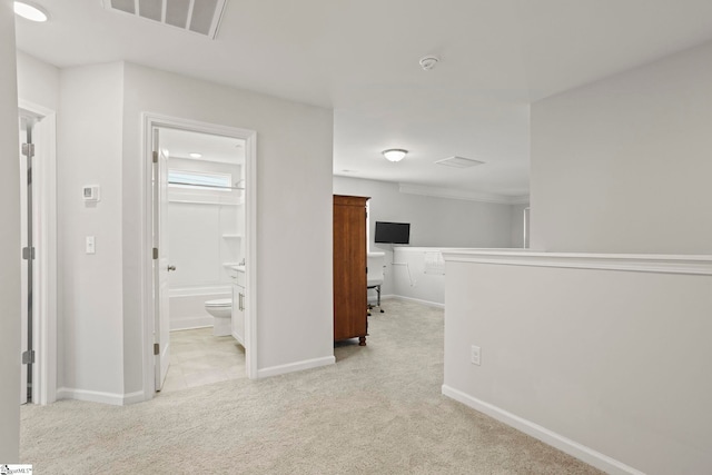 corridor featuring light carpet, visible vents, and baseboards