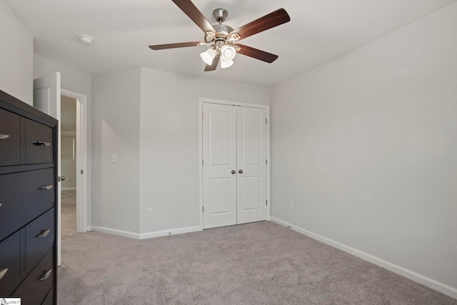 unfurnished bedroom with a closet, light carpet, ceiling fan, and baseboards