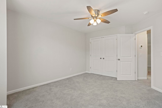 unfurnished bedroom with baseboards, a closet, a ceiling fan, and light colored carpet