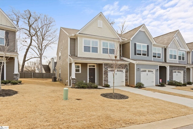 view of property featuring a garage, driveway, stone siding, and fence