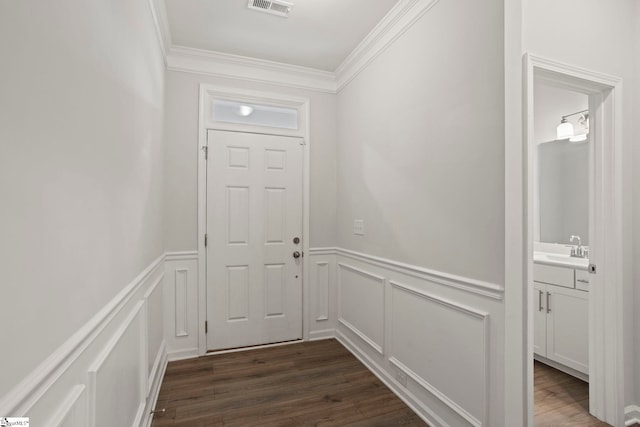 doorway featuring ornamental molding, dark wood finished floors, a decorative wall, and a sink