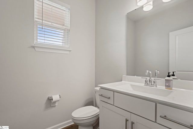 bathroom with toilet, vanity, and baseboards