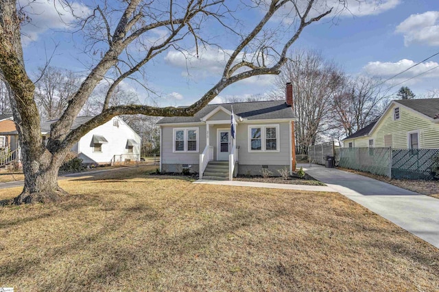 bungalow-style home with crawl space, fence, a chimney, and a front lawn