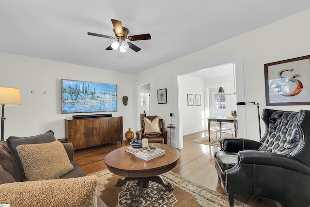 living room featuring ceiling fan, wood finished floors, and baseboards