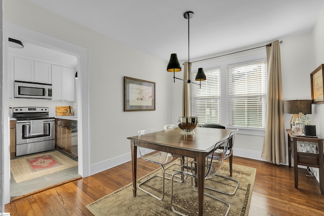 dining space featuring dark wood finished floors and baseboards