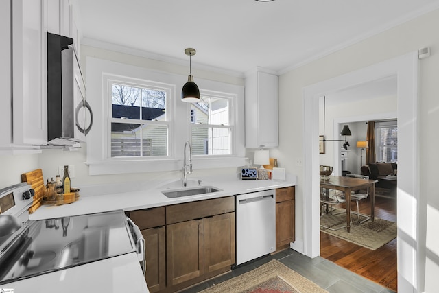 kitchen featuring light countertops, hanging light fixtures, appliances with stainless steel finishes, ornamental molding, and a sink