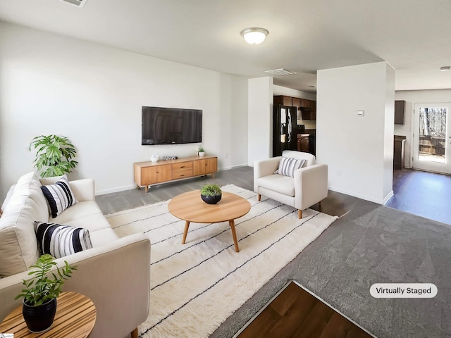 living area with dark wood-type flooring, visible vents, and baseboards