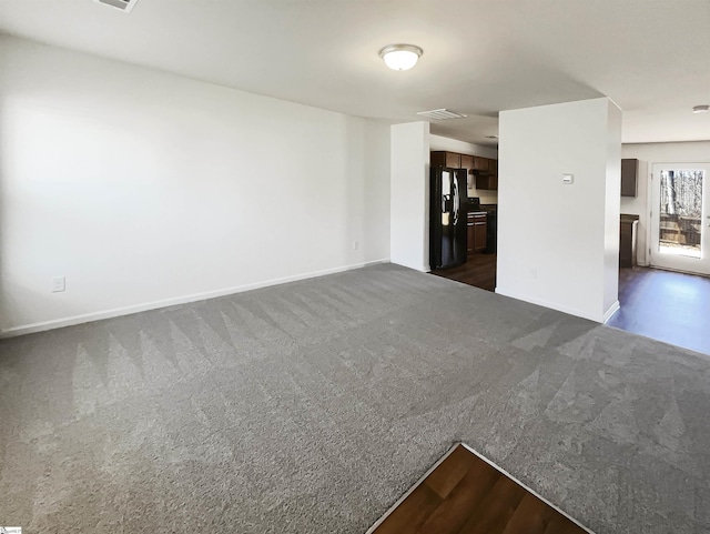 empty room featuring baseboards, visible vents, and dark carpet