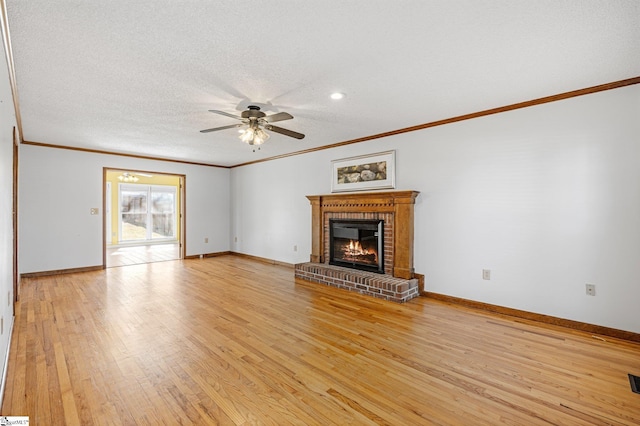 unfurnished living room with light wood-type flooring, a fireplace, a textured ceiling, and baseboards