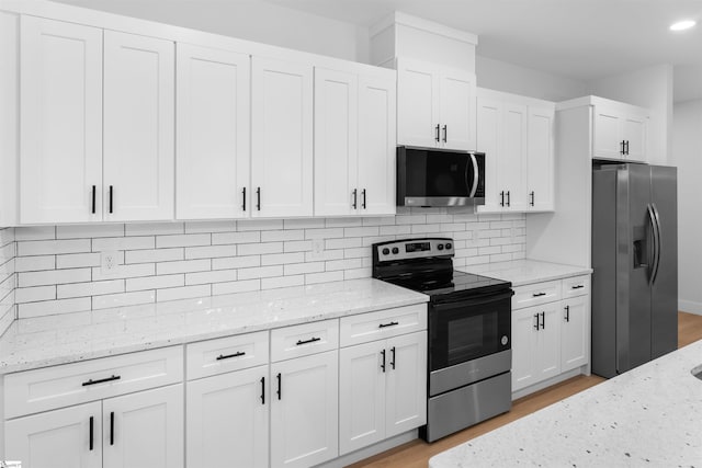 kitchen featuring stainless steel appliances, white cabinetry, and light stone countertops