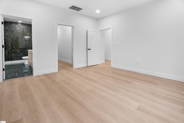 unfurnished bedroom with light wood finished floors, baseboards, a spacious closet, and visible vents